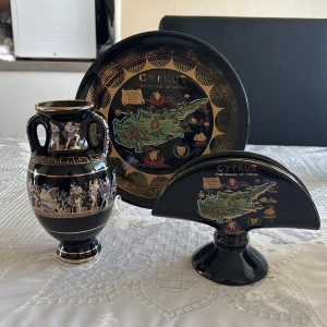 Tre fina antik souvenirer från Cypern  - Bilderna visar vackra souvenirer från Cypern, inklusive en vas och tallrik med antika grekiska motiv och en karta över ön. Dessa föremål är dekorerade med guld och färgglada illustrationer, perfekta för dig som gillar historia, konst och resor. Ingen bok syns på bilderna.