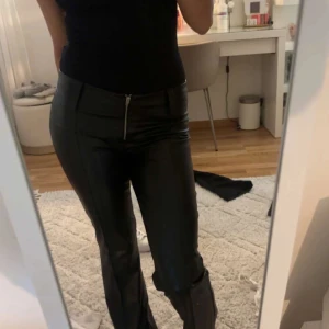 Svarta bootcut byxor i skinnimitation - Snygga svarta byxor i skinnimitation med bootcut-ben och låg midja Byxorna har dragkedja framtill och sitter tajt upptill med utsvängda ben. Bra skick då de aldrig används. Pris kan diskuteras ❤️