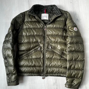 Olivgrön Moncler Jacka - Tja!säljer nu min riktigt feta Moncler jacka i storken 2 som motsvarar storlek M den passar den är är 165-175cm lång, den är i fint skick de ända är lagningarna på ryggen som inte syns och man tänker absolut inte på de, skriv om ni har några frågor eller funderingar🙌🙌🙌