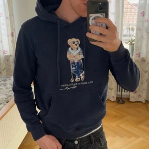 Mörkblå Polo Bear hoodie från Ralph Lauren - Säljer en mörkblå Ralph Lauren bear hoodie. I bra skicka! Kom gärna med frågor! Storlek M. Nån mörkare fläck endast som inte syns tydligt