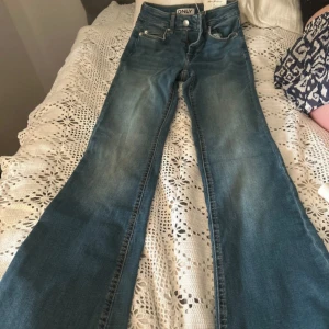 Blå flared jeans från ONLY XS - Snygga blå jeans från ONLY i modellen Blush med flared ben och midwaist. Jeansen har klassisk femficksdesign, dragkedja och knapp framtill. Tillverkade i mjuk denim med lätt tvättad look. 