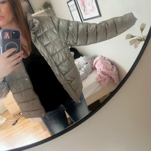 Grå Zara jacka - Säljer en grå jacka med glansig finish. Storleken är barnstorlek i 164. Jag brukar ha s i mina kläder, är ca 165 och jackan är lite liten på mig. Den har inga defekter förutom ett hål längst ner vid dragkedjan men den funkar lika bra ändå🥰