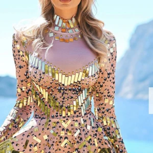 Born in Stockholm Glittrig rosa kortklänning med speglar - Ny med prislapp Superunik rosa kortklänning med lång ärm, täckt av glittriga guld- och silverspeglar samt svarta detaljer. Hög hals och figurnära passform, perfekt för dig som vill sticka ut. Klänningen har coola paljettdetaljer och ett spexigt mönster som verkligen fångar blicken.