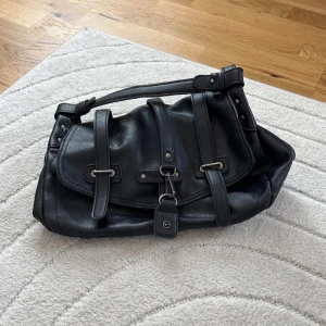 Svart handväska från Tamaris - Väskan är i bra skick och har varit väl omhändertagen. Det finns få tecken på att väskan har använts.