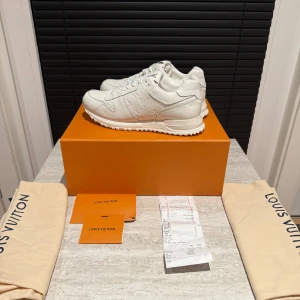 Louis Vuitton Run Away sneakers vit - Exklusiva Louis Vuitton Run Away sneakers i helvitt skinn med präglad LV-logga på sidan och tungan. Klassisk rund tå, snörning och robust sula. Storlek 43.