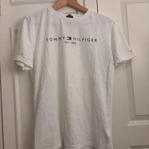 T-shirt från Tommy Hilfiger - Vit t-shirt från Tommy Hilfiger med tryckt logga och text på bröstet.