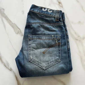 Dondup jeans - Säljer ett par blå jeans från Dondup med slitningar. Jeansen har en klassisk femficksdesign, raka ben och snyggt tvättad finish. Perfekta för dig som gillar en avslappnad men trendig look. Tyvärr finns det små fläckar (sista bilden) men inget som påverkar helhetsintrycket.