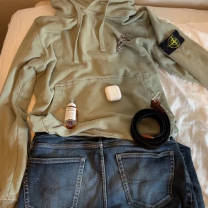 Ljusgrön hoodie från Stone Island - Säljer en snygg ljusgrön hoodie från Stone Island med klassisk patch på ärmen. Tröjan har huva med snörning, stor magficka och ribbade muddar. Perfekt för dig som gillar streetwear och vill ha något stilrent men ändå unikt. Tröjan är i riktigt bra skick säljer för att jag inte passar i färgen