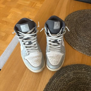 Nike Air Jordan 1 High Grå/Vit - Säljer ett par Nike Air Jordan 1 High i grått, vitt och svart. De var välanvända för några år sedan, sen har de legat på mitt rum utan användning. Så tänkte att jag lika gärna kunde sälja de. Finns syndliga defekter därav priset. Hör av dig vid frågor!