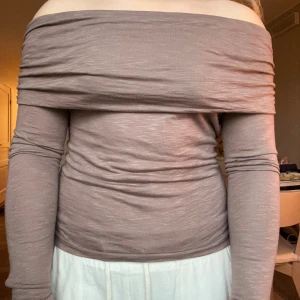 Beige offshoulder topp med rynkade ärmar - Säljer en beige offshoulder topp med långa ärmar och snygga rynkade detaljer längs axlarna. Mjukt och skönt material, säljer då den tyvärr inte kommer till användning🤗