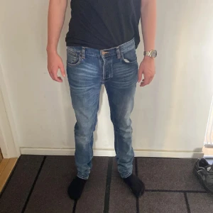 Nudie Jeans  - Säljer ett par Nudie Jeans Tilted Tor i färgen True Cold Blue. Jeansen är blå med snygga slitningar och klassiska orange sömmar. Modellen har normal passform och raka ben. Materialet är 99% ekologisk bomull och 1% elastan för lite stretch. Modellen är 178 cm lång och väger 63 kg. Det är bara att höra av sig vid frågor och funderingar 😀