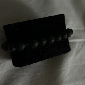 Svart pärlarmband (lavastenar) - Stilrent svart armband med runda pärlor av lavasten. Pärlorna har en matt, lite porös yta som ger en cool och unik känsla. Perfekt accessoar för dig som gillar minimalistisk och naturlig stil.