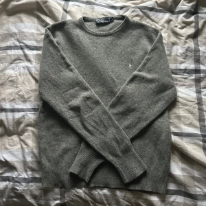 Grå ulltröja från Polo Ralph Lauren - Klassisk grå rundhalsad tröja från Polo Ralph Lauren i mjuk ull. Strl M. Tröjan har ribbade muddar vid ärmslut och nederkant samt en liten broderad logga på bröstet. Perfekt för lager-på-lager och stilren look. Riktigt skön nu under höst/vinter. Pris är inte fast, kom med prisförslag! Vid fler frågor är det bara att kontakta🤩