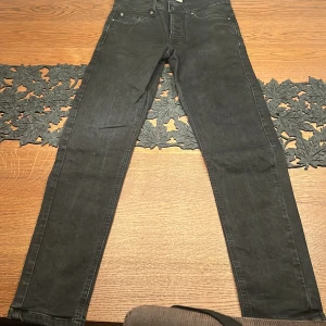 Svarta jeans The Blue Uniform - Svarta jeans från The Blue Uniform med klassisk femficksdesign och smal passform. Jeansen har bälteshällor, knappgylf, diskreta sömmar och Väldigt snygga detaljer 