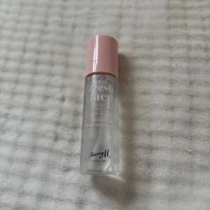 Barry M Fresh Face Dewy Setting Spray - Fräsch setting spray från Barry M med gurka och snösvamp. Kommer i en genomskinlig plastflaska med ljusrosa lock. Perfekt för att fixera sminket och ge en återfuktad, glowig finish. Vegansk och cruelty free.
