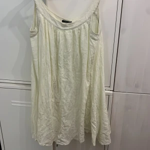 Samsøe Samsøe vit bomulls  klänning - Supersöt vit klänning från Samsøe Samsøe i modellen Kiwa Dress. Den är ärmlös, har en lös passform och är gjord i krinklad bomull som ger en chill och luftig känsla. Några skavanker men fortsatt mycket kvar att ge.