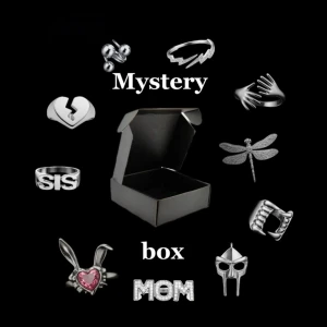 Mystery box silver  - Mystery box fylld med unika silverfärgade ringar i olika former, som hjärta, kanin med rosa sten, drakflyg, vampyrtänder, masker och text som SIS och MOM. Perfekt för dig som gillar att överraska dig själv med snygga accessoarer. (Obs endast 1 Pär box, vid beställning av bundle får man alltid 2 olika!)