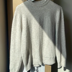 Beige stickad tröja från LMTD XS - Mysig beige stickad tröja från LMTD i storlek XS. Tröjan har en rund halsringning och ribbade muddar vid ärmslut och nederkant. Materialet är mjukt och fluffigt, perfekt för kyliga dagar. Enkel och stilren design som är lätt att matcha med dina favoritjeans.