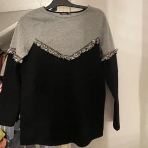 Grå och svart tröja med fransdetalj Boohoo -  långärmad tröja från Boohoo i grått och svart med fransdetaljer längs bröstet och ärmarna. 