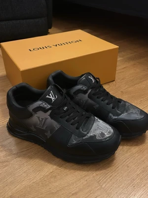 Louis Vuitton svarta sneakers monogram 42.5 - KÖPTA I DUBAI MALL använda ett antal gånger.  Svarta Louis Vuitton sneakers med ikoniskt LV-mönster i grått och svart på sidorna och tån. Skorna har rund tå, platt sula och snörning. Tillverkade i skinn med detaljer i syntet. Märkeslogga på plös och häl. Levereras med originalkartong och dustbag.