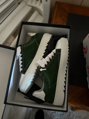 Gröna sneakers från Numeris - Säljer ett par snygga gröna sneakers från Numeris med vit platt sula och vit häl. Ovandelen är i mocka och har vita, breda snören samt vit tå. Snygga detaljer med kontrastsömmar och räfflad sula som ger extra edge. 