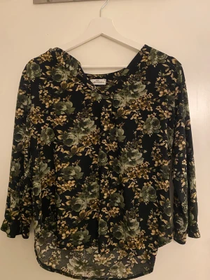 Blommig svart blus - stl S - Blommig blus i svart med gröna/beige toner och trekvartsärm. Lätt och luftig modell, perfekt till vardag eller fest. Använd fåtal gånger, mycket fint skick. Storlek S. 