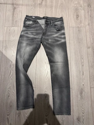 Jack & Jones Slim Fit Glenn jeans grå - Slim fit Glenn jeans från Jack & Jones i en snygg grå tvätt med blekta detaljer. Klassisk femficksmodell med raka ben och normal passform. Jeansen är tillverkade i mjukt bomullsmaterial och har en modern look som passar till sneakers eller boots.