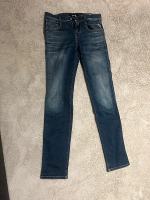 Replay blå jeans, storlek 29 - Säljer ett par snygga blå jeans från Replay i storlek 29. Jeansen har klassisk femficksdesign, dragkedja och knapp, samt diskreta slitningar för en cool look. Passformen är rak och materialet är mjukt denim som sitter skönt hela dagen.