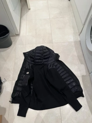 Svart Moncler cardigan  - Moncler cardigan ganska ny, säljes billigt pågrund av litet hål och nån fläck som syns på bild  Storlek M  Går säkert att sy ihop!