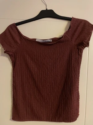 Vinröd ribbad topp från 157 - Säljer en vinröd ribbad topp från 157 i storlek S. Toppen har korta ärmar och en lätt croppad passform med stretchigt material. Perfekt att styla med jeans eller kjol för en chill look. Materialet är mjukt och har en snygg struktur.