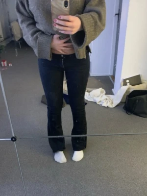 Svarta lågmidjade bootcut jeans - Säljer ett par svarta jeans med bootcut-modell och låg midja. Jeansen har klassisk femficksdesign och stängs med knapp och dragkedja. Perfekta för dig som gillar en tidlös och snygg look.