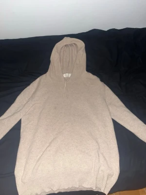 Beige kashmirhoddie från Sayless - Mysig beige hoodie med huva och dragsko. Tröjan är långärmad och har en enkel, stilren design. Tillverkad i mjuk kashmirblandning som känns lyxig mot huden. Perfekt för dig som gillar en chill och avslappnad look. Priset är fast 