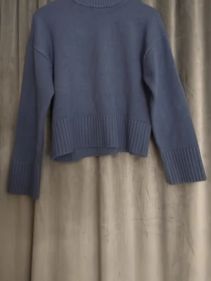 Blå stickad polotröja från H&M - Säljer en blå stickad polotröja från H&M i storlek S. Tröjan har ribbade detaljer vid hals, ärmslut och nederkant, samt en loose passform med långärmade ärmar. Perfekt för dig som gillar enkel och stilren design.