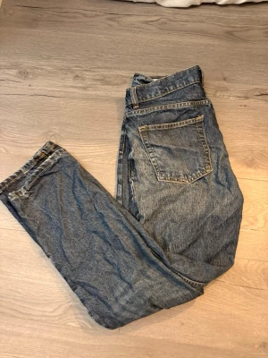 Blå jeans från Vaient, straight fit - Säljer ett par klassiska blå jeans från Vaient med straight fit och regular waist. Jeansen har fem fickor, gylf med dragkedja och snygga kontrastsömmar. Materialet är slitstarkt denim i bomull och passformen är normal. Perfekt för dig som gillar enkel och tidlös stil.