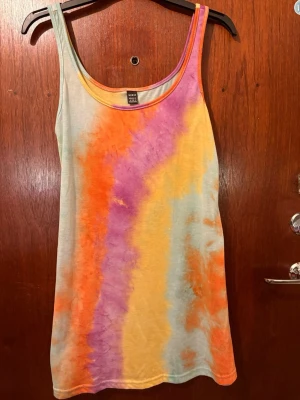 Färgglad tie-dye linnetopp från SHEIN - Säljer en cool och färgglad linnetopp från SHEIN i storlek M. Toppen har ett tie-dye mönster i orange, lila, gul och ljusblå toner. Modellen är ärmlös med rundad hals och tillverkad i mjuk bomull. Perfekt för sommarens alla häng!