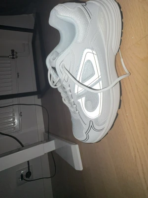 Vita d sneakers  - Säljer ett par vita bior sneakers med chunky svart och vit sula. Skorna har snörning, meshpaneler och reflekterande detaljer på sidan. Snyggt mönstrad yttersula med D-logga undertill. Perfekt för dig som gillar exklusiva och trendiga sneakers.