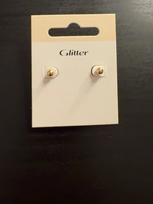 Guldiga örhängen  - Säljer ett par fina guld örhängen från glitter, de är oanvända och i bra skick💗