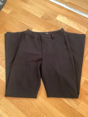 Svarta kostymbyxor från Bik Bok - Snygga svarta kostymbyxor från Bik Bok med klassisk rak passform. Byxorna har bälteshällor och diskreta sidofickor, perfekta för en clean och stilren look. Materialet är mjukt och känns bekvämt mot huden.