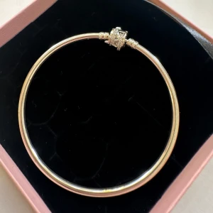 Pandora armband  - Pandora Moments Sparkling Shooting Star Clasp Bangle köpt från Pandora för ca 1 år sedan men kom aldrig till användning.  De två korsberlocker tillkommer inte, utan säljs separat. Men om man vill ha med de så kan man skriva det till mig så löser jag det. 
