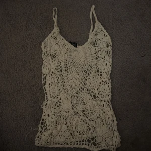 Virkat linnetopp från Free People - Säljer en virkad linnetopp från Free People i vit. Toppen har tunna axelband och ett detaljerat blommigt mönster med genombruten spets. Den har typ 2 hål på sidan men har inte märkt de innan då de smälter in med spetsmönstret💞