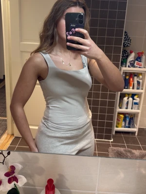 Beige ärmlös linnetopp Square neck tank top - Snygg beige linnetopp i bomull med breda axelband och rundad halsringning. Toppen är figurnära och har en enkel, stilren design som passar perfekt till jeans eller kjol. Materialet känns mjukt och bekvämt mot huden. Nypris 160kr