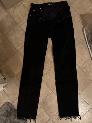 Svarta jeans från Mavi Gold - Säljer ett par svarta jeans från Mavi Gold med klassisk femficksdesign och råa, fransiga benslut. Jeansen har normal passform och raka ben. Materialet är slitstarkt jeans och färgen är helt svart. Perfekta till sneakers eller boots.