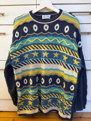 Vintage 1992, mönstrad stickad tröja Benetton storlek S (oversized) - Vintage 1992! Färgglad stickad tröja från United Colors of Benetton i 100% bomull. Tröjan har ett unikt mönster med stjärnor, cirklar och vågiga linjer i blått, gult, vitt och turkost. Långärmad och loose fit. Perfekt skick!