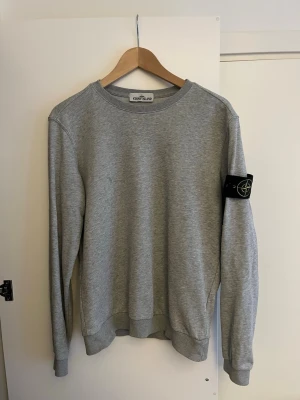 Grå sweatshirt från Stone Island - Säljer en stilren grå sweatshirt från Stone Island som jag säljer billigt då jag inte har nån användning för den. Pris kan diskuteras vid snabb affär