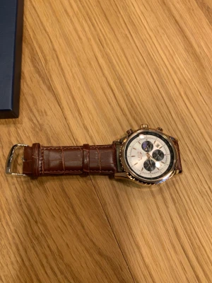 Brun klocka från Lige  - Bilderna visar en klocka från LIGE med brun läderrem och vit urtavla. Helt ny skick. Priset går att förhandlas.