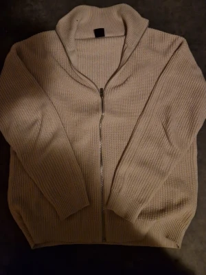 Beige sstickad zip-tröja - Säljer en beige stickad zip. Helt ny inga defekter alls. Storlek S men sitter rätt bra på xs också. Materialet är 100 procent cotton. Håller dig rätt varm och är ganska skön