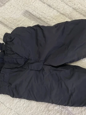 Svarta täckbyxor med resårmidja - Termobyxor  Perfekta för kalla dagar och vinteraktiviteter. Byxorna är rymliga och har en klassisk look som funkar till det mesta utomhus.