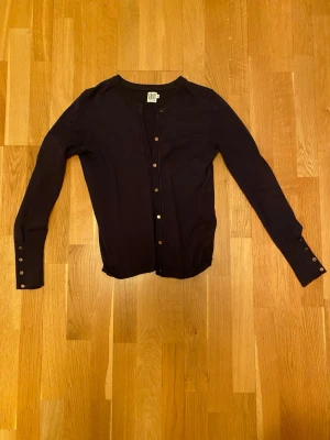Svart kofta från Saint Tropez - Säljer en svart kofta från Saint Tropez i storlek S. Koftan har långa ärmar och knappar framtill samt vid ärmsluten. Enkel och stilren modell som passar till det mesta. Materialet känns mjukt och lätt, perfekt för lager på lager.