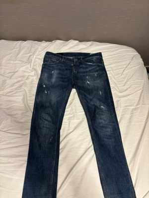 Dondup mörkblå jeans - Säljer ett par mörkblå skinny jeans från Dondup i storlek 32. Jeansen har slitna detaljer och skön tvätt . Modellen är George. Perfekta för dig som gillar en modern och small passform