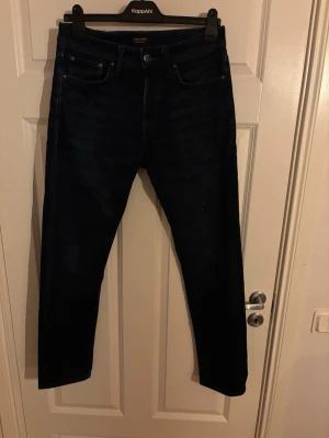 Mörkblå jeans från Jack & Jones - Snygga mörkblå jeans från Jack & Jones med klassisk femficksdesign och raka ben. Jeansen har en stilren look med normal passform och är tillverkade i mjukt denimtyg. Perfekta för dig som gillar enkel och tidlös stil.  Pris kan diskuteras